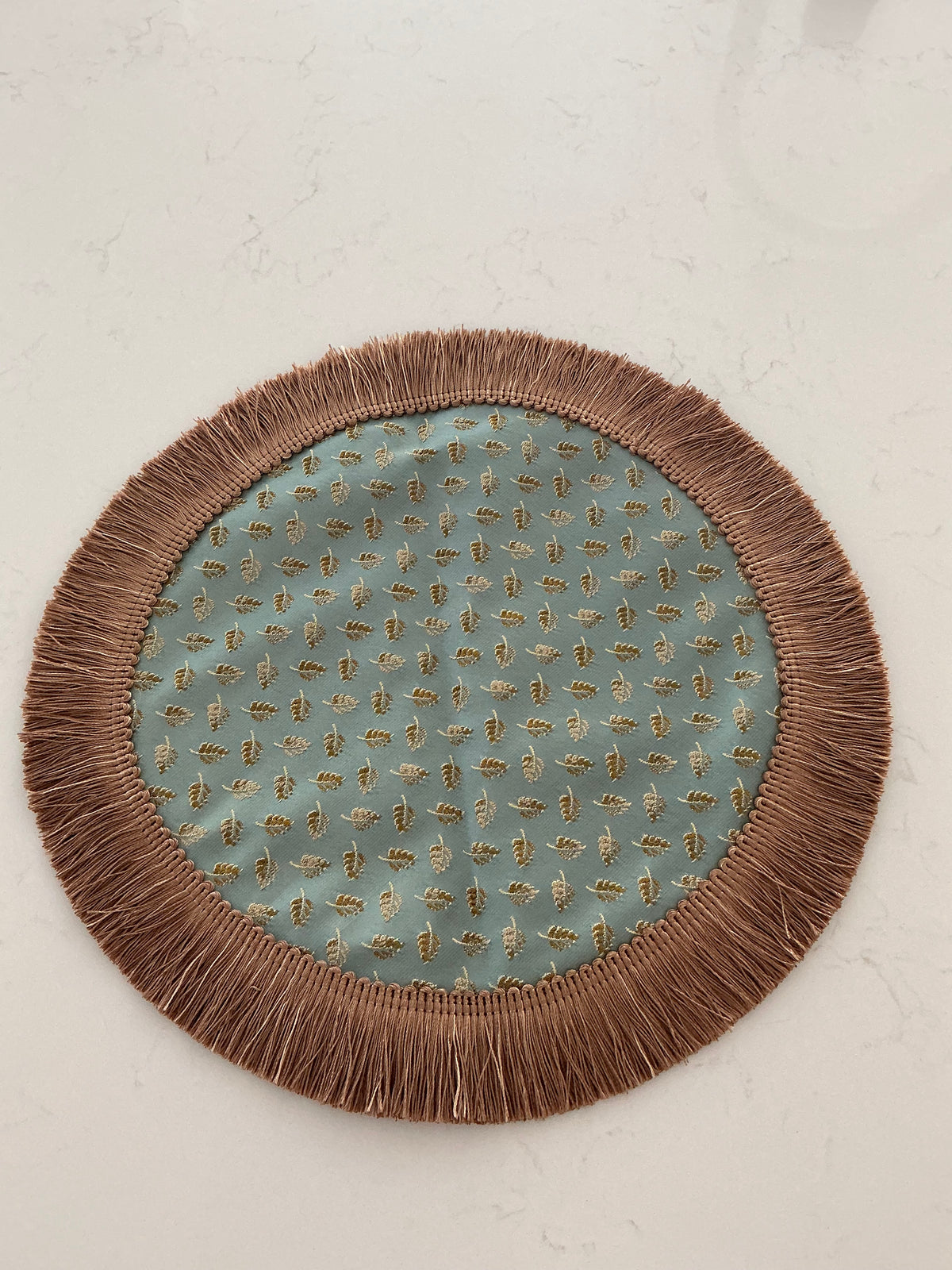 Ornate round table topper in sage green and copper jacquard with scattered leaf motif and tassel fringe border