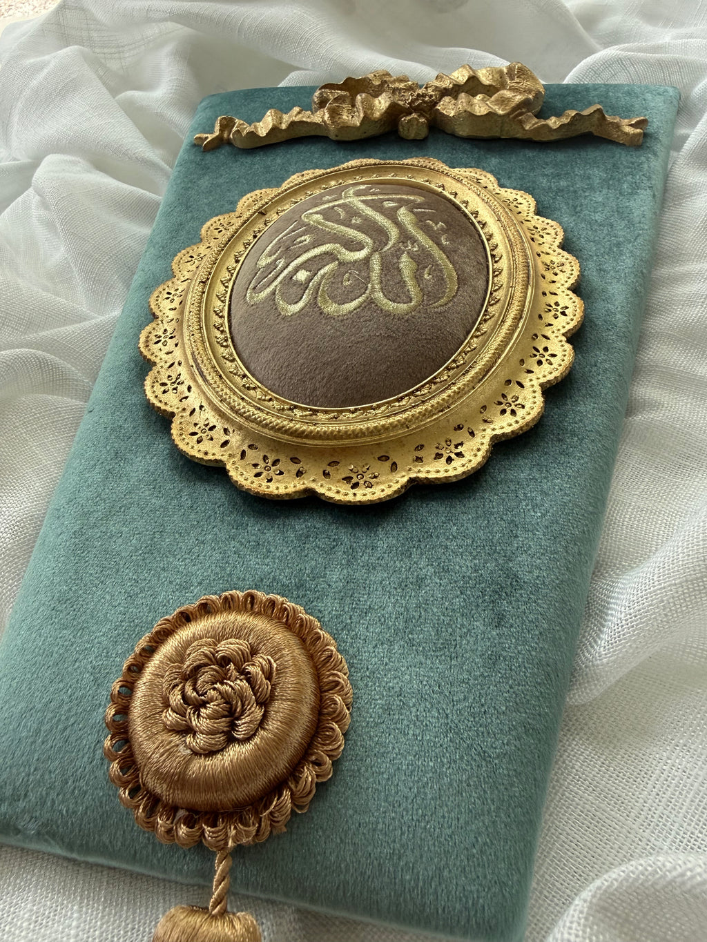 Close-up of Islamic calligraphy wall hanging showing Alhamdulillah medallion with gold frame and tassel detail