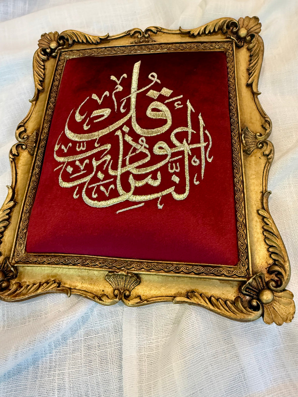 Ornate antique gold framed Islamic calligraphy artwork on burgundy background